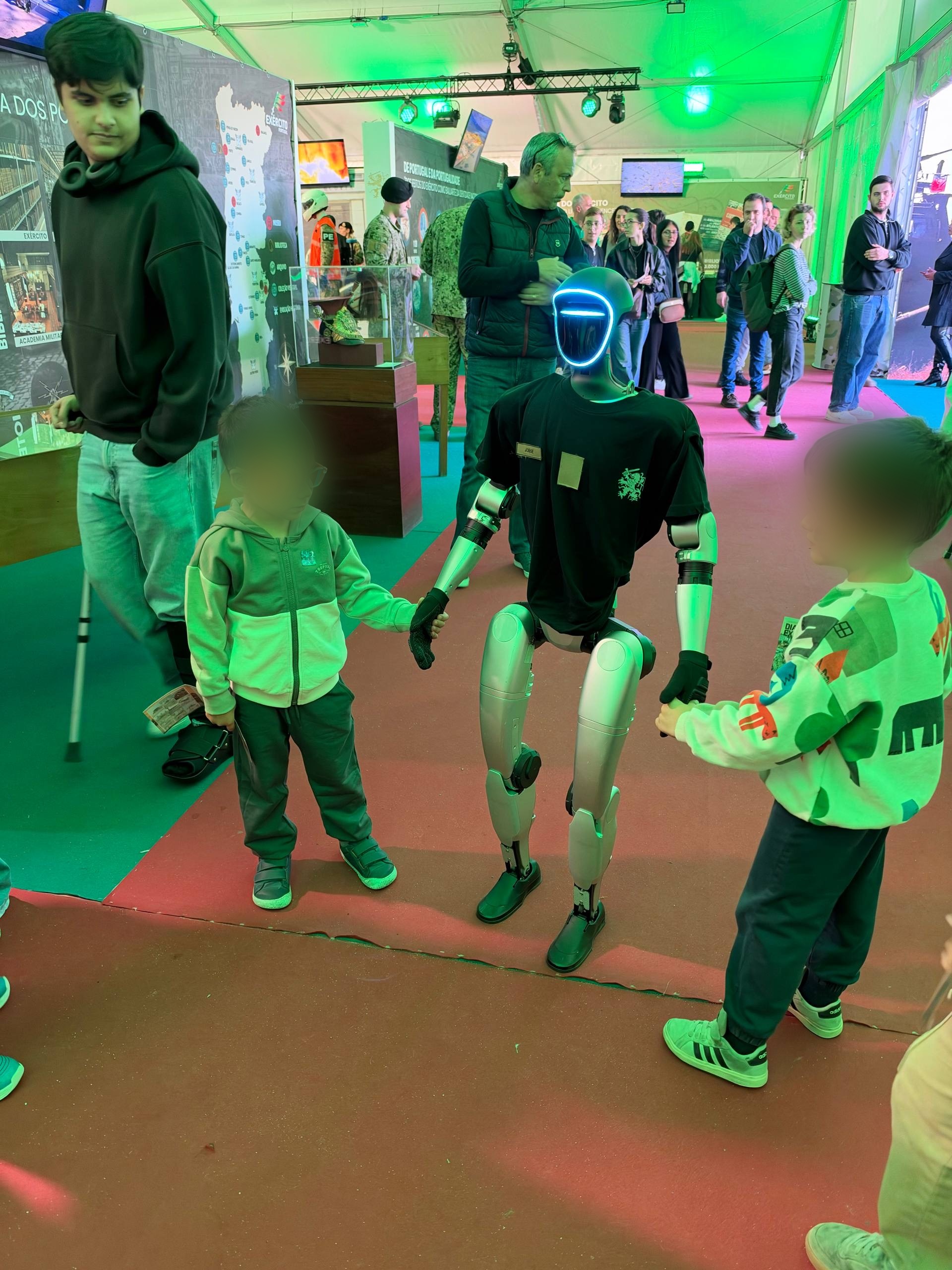The humanoid in a Portuguese Army shirt holding hands with two kids at Dia do Exército
